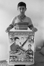 Boy in Balata holding brother's memorial poster